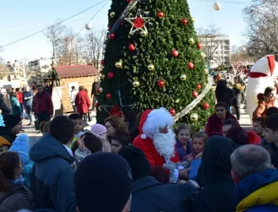Дядо Коледа раздава подаръци на децата край елхата на площад 